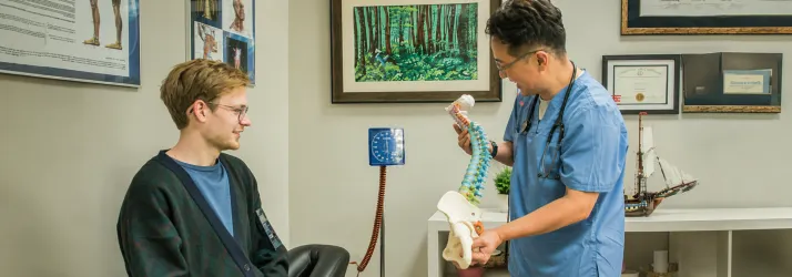 Chiropractor in Duluth GA Chuel Hong Park showing a spine model to a patient.